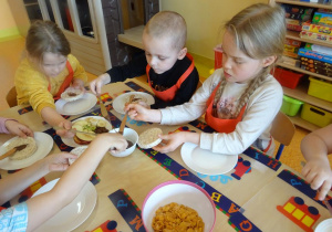 Dzieci smarują czekoladą wafle ryżowe.